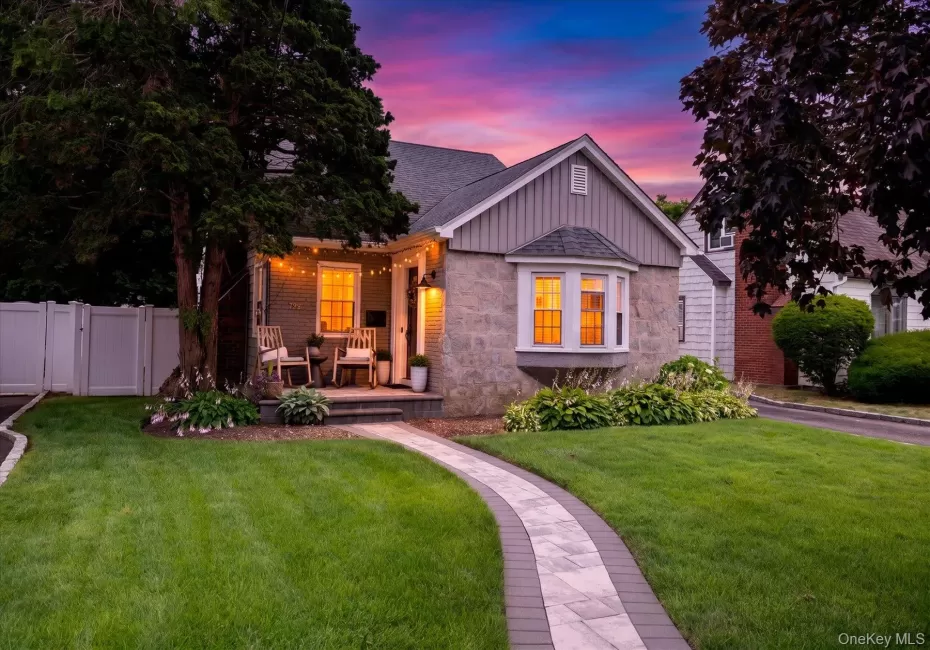 Stone and siding exterior featuring a front porch, bay window, paver walkway, and a manicured lawn Stone and siding exterior featuring a front porch, bay window, paver walkway, and a manicured lawn