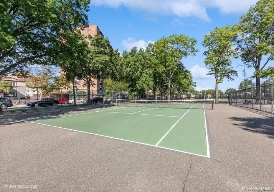 Outdoor tennis court with green playing surface and white line markings Outdoor tennis court with green playing surface and white line markings