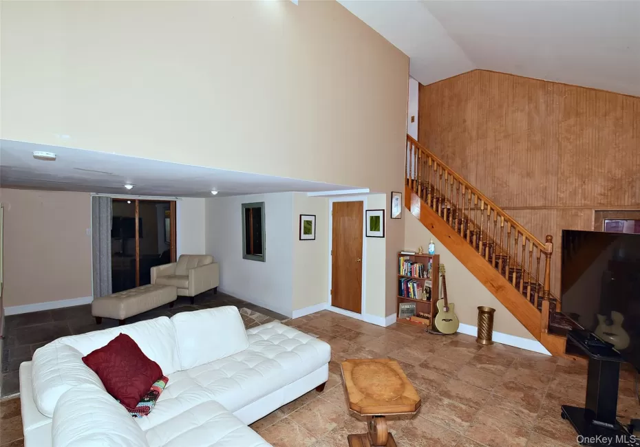 Living room with baseboards, stairway, and high vaulted ceiling Living room with baseboards, stairway, and high vaulted ceiling