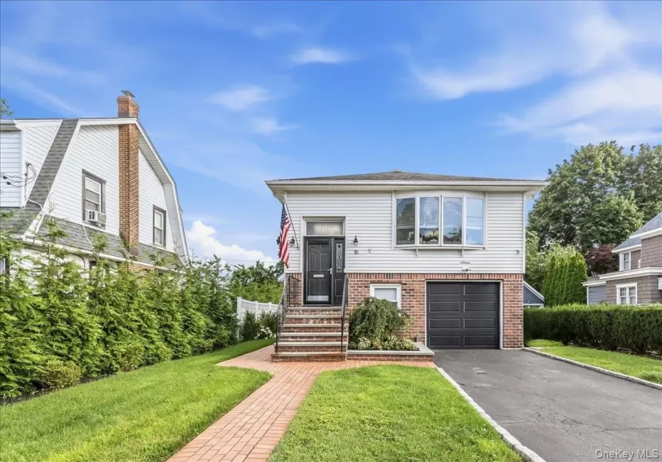 Contemporary residence featuring a brick walkway, manicured lawn, and an attached garage Contemporary residence featuring a brick walkway, manicured lawn, and an attached garage