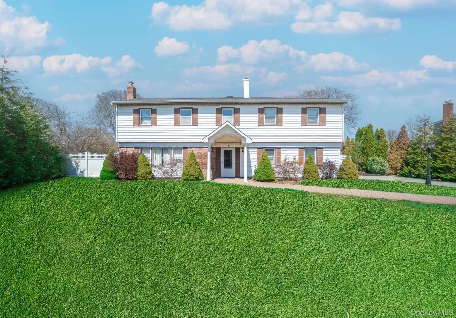 Colonial inspired home with a chimney, a front lawn, and fence Colonial inspired home with a chimney, a front lawn, and fence