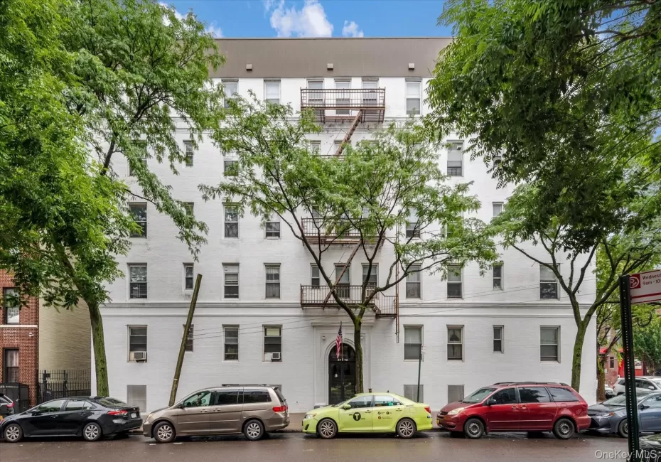 White multi-story building featuring numerous windows and an arched entryway White multi-story building featuring numerous windows and an arched entryway