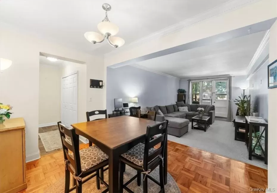 Dining room featuring light parquet floors, an inviting chandelier, and crown molding Dining room featuring light parquet floors, an inviting chandelier, and crown molding