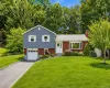 Split-level residence featuring a brick and blue siding exterior, an attached single-car garage, and a paved driveway Split-level residence featuring a brick and blue siding exterior, an attached single-car garage, and a paved driveway