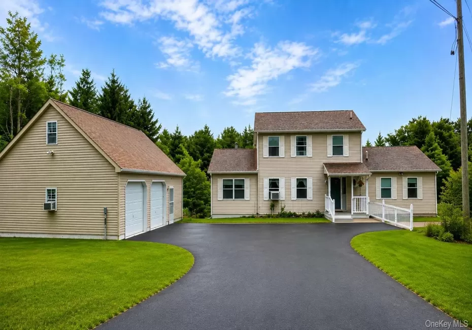 Expansive asphalt driveway leading to a two-story residence and a detached two-car garage Expansive asphalt driveway leading to a two-story residence and a detached two-car garage