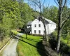 View of side of home with asphalt driveway, a lawn, and a wooded view View of side of home with asphalt driveway, a lawn, and a wooded view