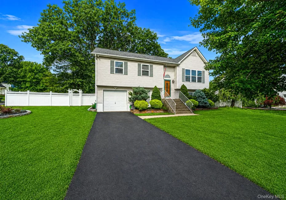 Hi-ranch featuring a single-car garage, white vinyl fencing, and a paved driveway Hi-ranch featuring a single-car garage, white vinyl fencing, and a paved driveway