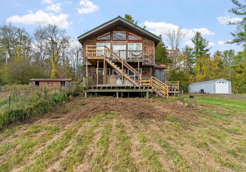 Back of property with an outdoor structure, a deck, and stairs Back of property with an outdoor structure, a deck, and stairs