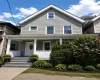 Traditional home featuring gray siding, a prominent gable roofline, and white trim Traditional home featuring gray siding, a prominent gable roofline, and white trim