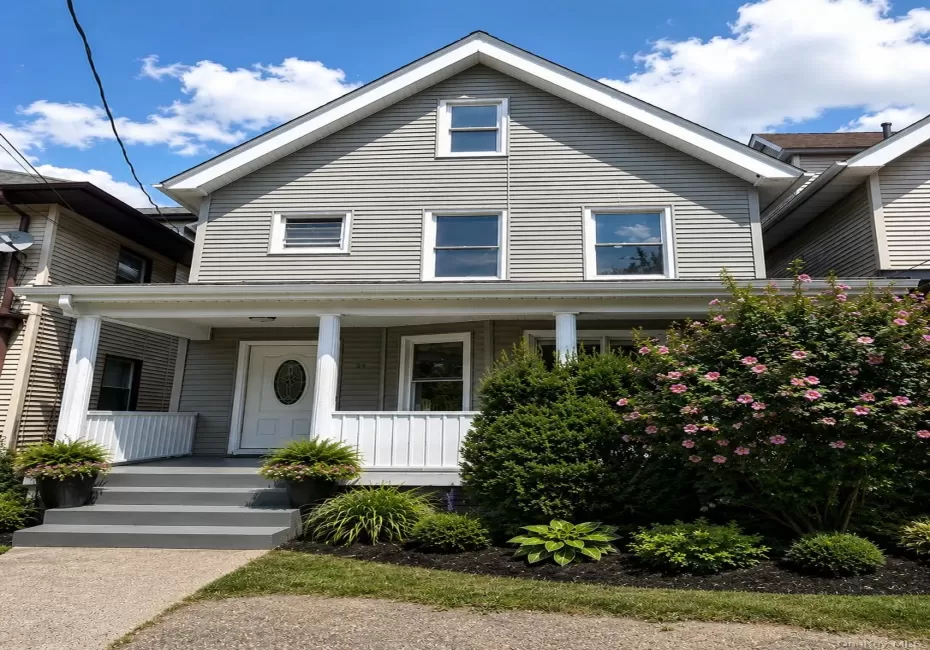 Traditional home featuring gray siding, a prominent gable roofline, and white trim Traditional home featuring gray siding, a prominent gable roofline, and white trim