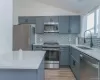 Kitchen with lofted ceiling, stainless steel appliances, light stone countertops, tasteful backsplash, and gray cabinets Kitchen with lofted ceiling, stainless steel appliances, light stone countertops, tasteful backsplash, and gray cabinets