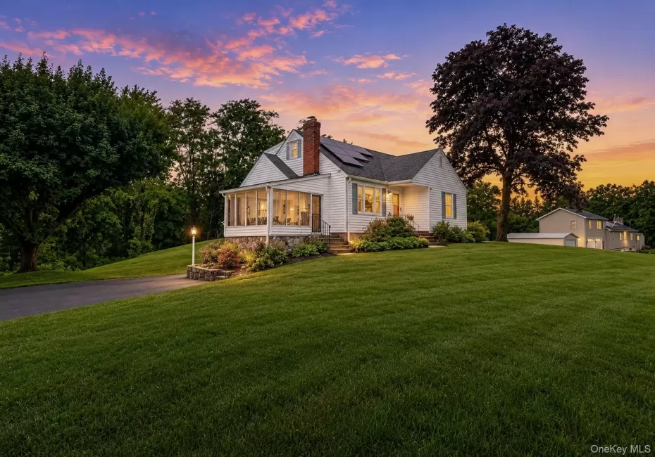 White siding residence featuring a screened porch, prominent chimney, and multiple solar panels White siding residence featuring a screened porch, prominent chimney, and multiple solar panels