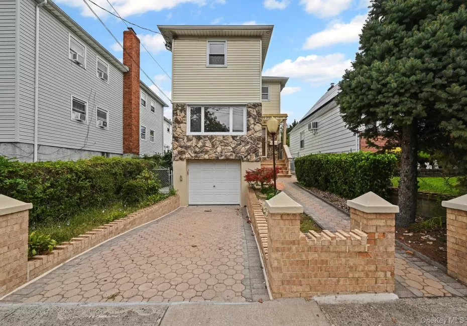 View of front facade with decorative driveway, stone siding, and an attached garage View of front facade with decorative driveway, stone siding, and an attached garage