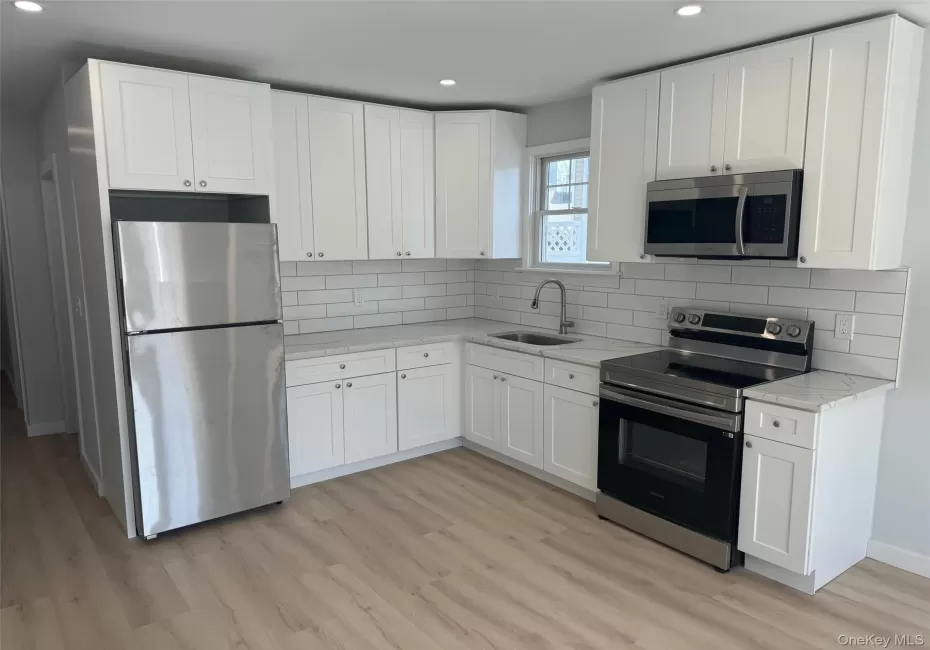 Kitchen featuring appliances with stainless steel finishes, a sink, recessed lighting, light wood-type flooring, and white cabinets Kitchen featuring appliances with stainless steel finishes, a sink, recessed lighting, light wood-type flooring, and white cabinets