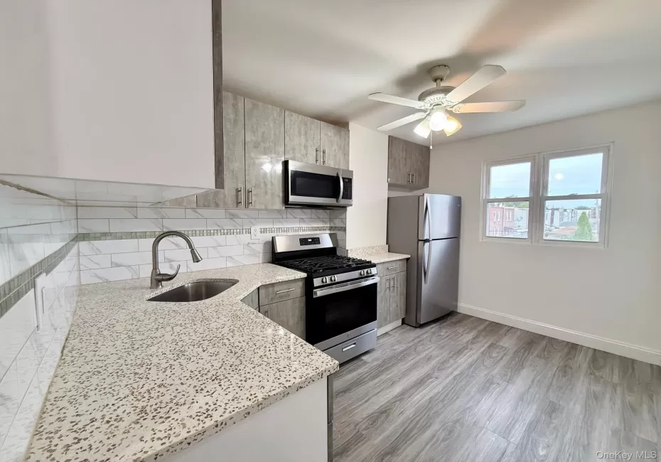 Kitchen featuring light wood-finish cabinetry, stainless steel appliances, speckled countertops, and a white subway tile backsplash Kitchen featuring light wood-finish cabinetry, stainless steel appliances, speckled countertops, and a white subway tile backsplash