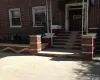 Brick facade with decorative brickwork, concrete steps, and a wrought iron porch railing Brick facade with decorative brickwork, concrete steps, and a wrought iron porch railing